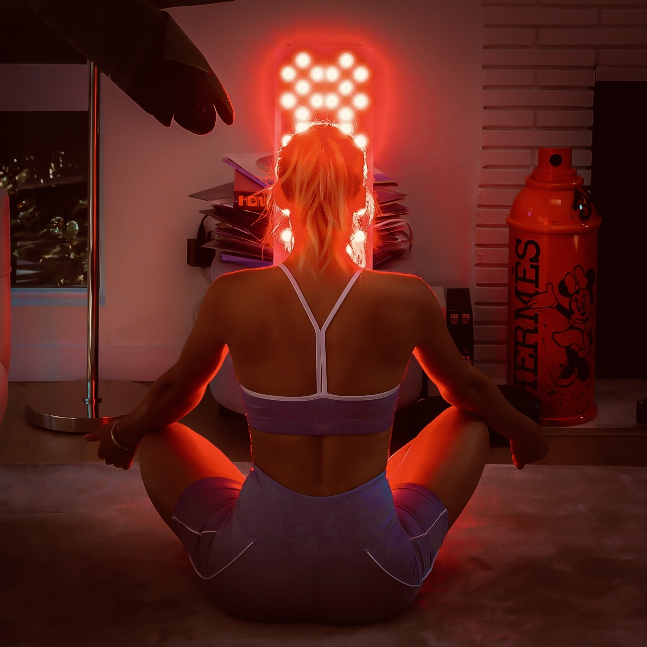 Woman meditating in front of a wall-mounted red light therapy panel